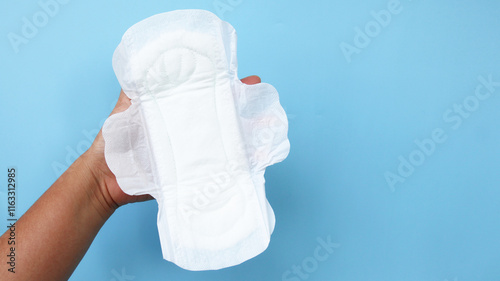  hand is holding Sanitary napkin on blue background. photo