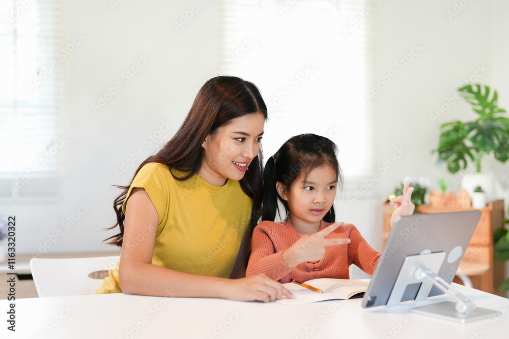 Asian little young girl kid learning online class at home with mother. Preschool child use laptop computer do homework, homeschool from school teacher by digital remote internet with support from mom. Asian little young girl kid learning online class at home with mother. Preschool child use laptop computer do homework, homeschool from school teacher by digital remote internet with support from mom.