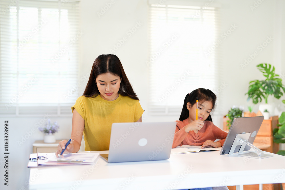 Mom working from home with distance learning child, multitasking childcare and work life balance . Single parent or mother and girl busy on laptop notebook and education Mom working from home with distance learning child, multitasking childcare and work life balance . Single parent or mother and girl busy on laptop notebook and education