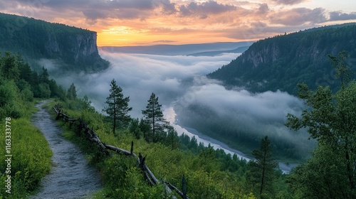Low clouds drifting over a lush mountain valley, revealing a winding river and a scenic road beneath a dynamic sky in the Ural mountains