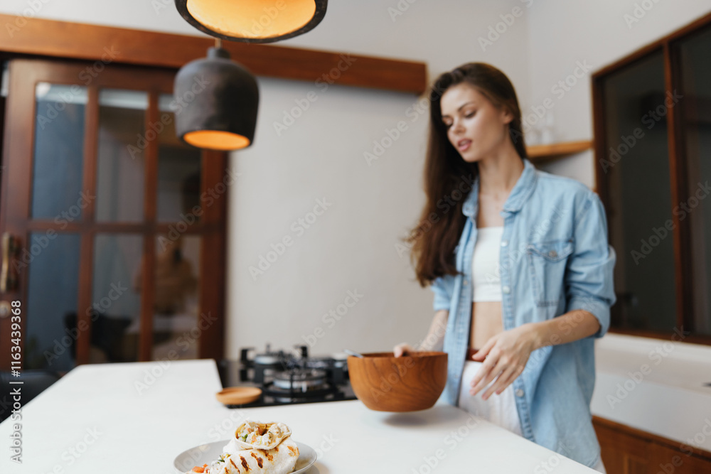 Young woman preparing healthy food in a modern kitchen, wearing casual clothes with a wooden bowl, focused on healthy eating and lifestyle, bright interior Young woman preparing healthy food in a modern kitchen, wearing casual clothes with a wooden bowl, focused on healthy eating and lifestyle, bright interior