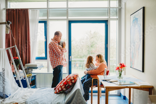 Family of 4 in hospital room with newborn baby photo