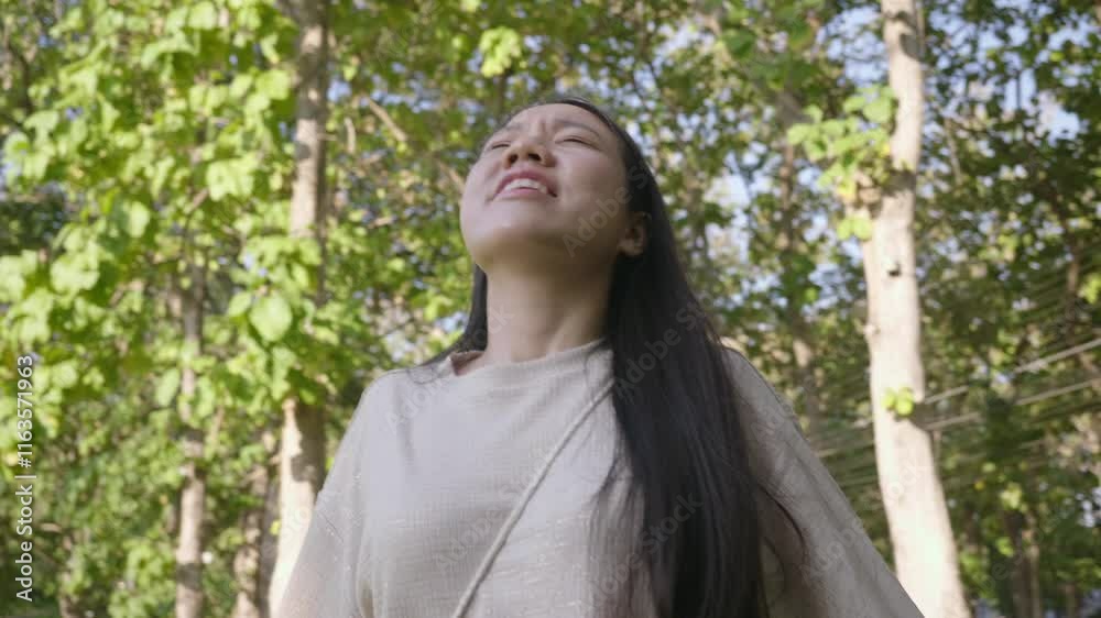 A woman with long hair is standing in a forest. She is looking up at the sky and she is crying A woman with long hair is standing in a forest. She is looking up at the sky and she is crying