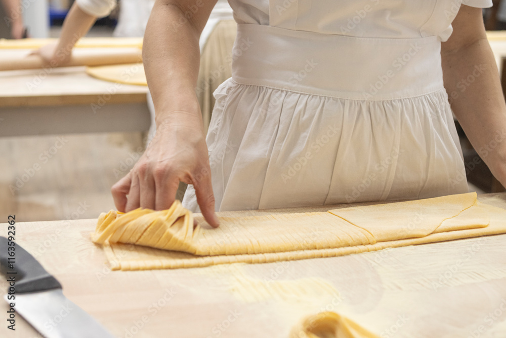 Traditional italian cook cutting pasta. Delicious homemade cuisine. Tagliatelle