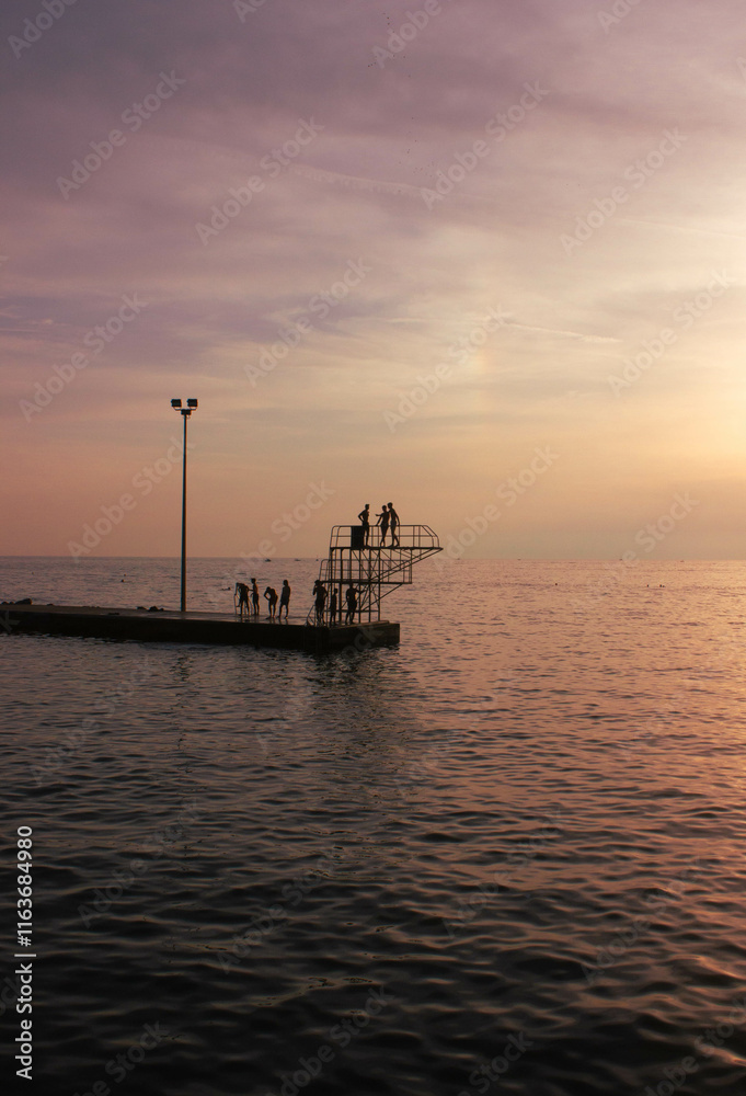 Obraz premium Bathers on the Adriatic Sea are taking advantage of the last rays of the sun to enjoy