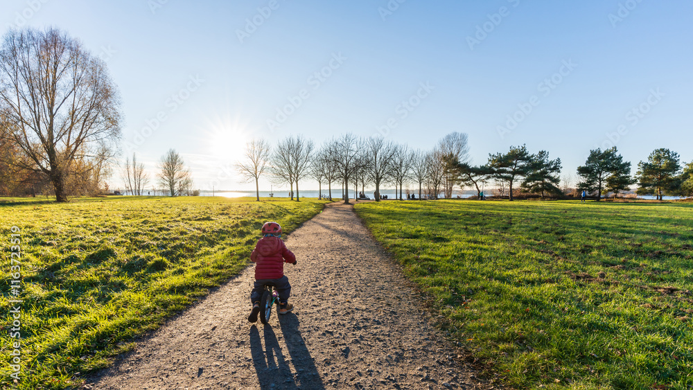 Obraz premium A young boy driving his bike at the Cospudener Lake in Leipzig in late autumn