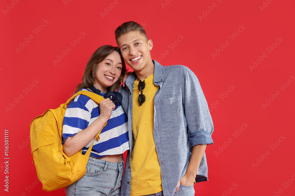 Naklejka premium Traveller with backpack. Happy young woman and man on red background