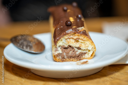 éclair au chocolat entamé dans une petite assiette photo