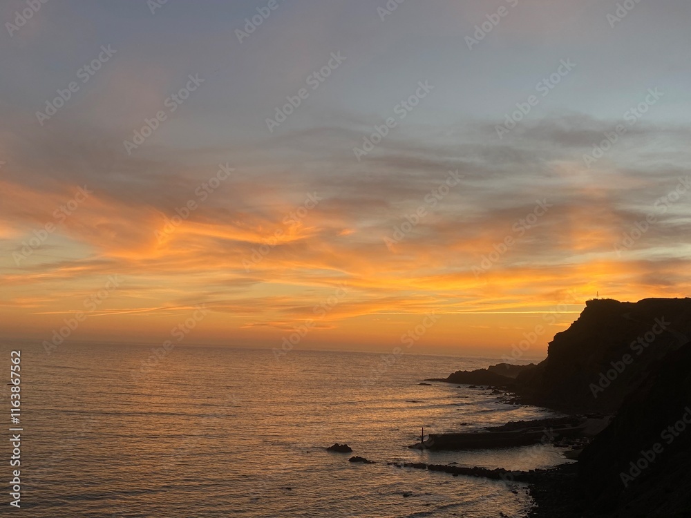 an orange evening sky formed with clouds hanging low over the ocean an orange evening sky formed with clouds hanging low over the ocean