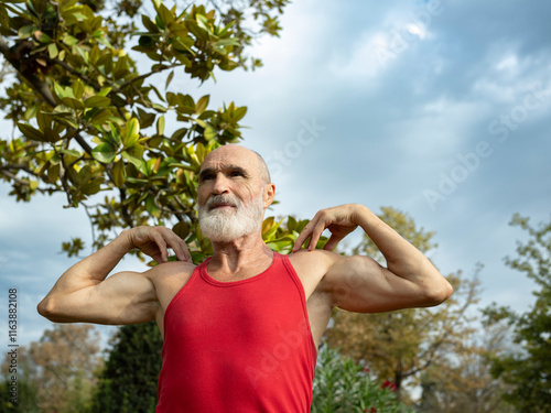 Senior man exercising near trees under cloudy sky photo