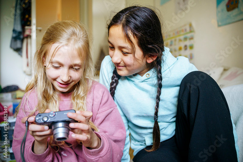 Multiracial friends looking at analog camera photo