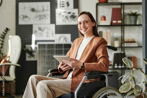 Cheerful businesswoman sitting in wheelchair at office photo