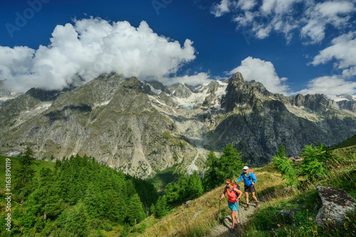 Man and woman hiking on footpath with Grandes Jorasses mountain in background photo