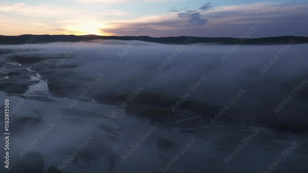 Discover the serenity of a river village enveloped in morning fog during an early aerial exploration Discover the serenity of a river village enveloped in morning fog during an early aerial exploration