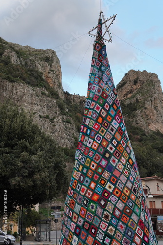 Unique and artistic urban Christmas tree, entirely handcrafted from crocheted fabric. A variety of multi-colored threads arranged in geometric patterns, a masterpiece of patchwork, painstaking handwor photo