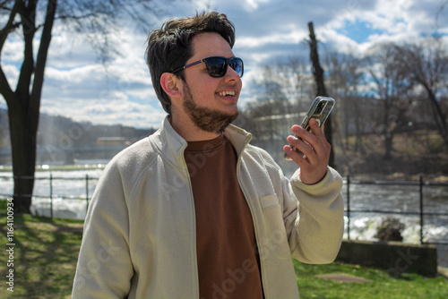 Latin young man holding a phone in paterson great falls national park new jersey photo