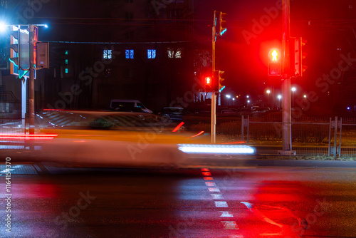 A blurred car drives down the street in the evening.