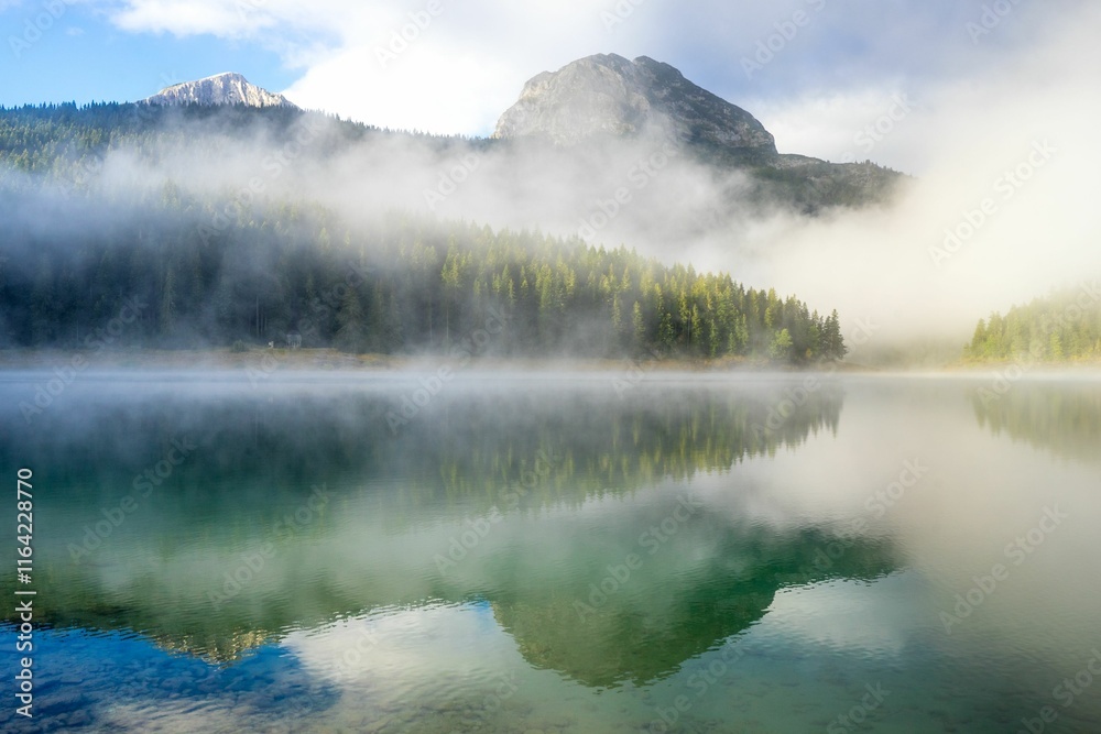 Serene mountain landscape with mist over a reflective lake, capturing the tranquility of nature. Serene mountain landscape with mist over a reflective lake, capturing the tranquility of nature.