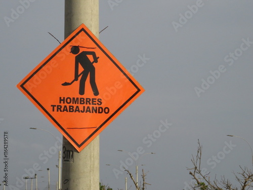 Señalización de seguridad en español, con mensaje de hombres trabajando.