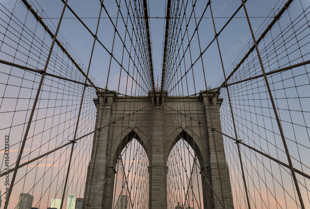 Obraz premium Brooklyn Bridge close up detail looking up at suspension cables at sunrise (beautiful landmark travel tourism destination in NYC) iconic New York City attraction over east river downtown Manhattan USA