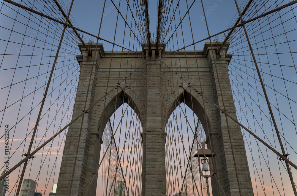 Fototapeta premium Brooklyn Bridge close up detail looking up at suspension cables at sunrise (beautiful landmark travel tourism destination in NYC) iconic New York City attraction over east river downtown Manhattan USA