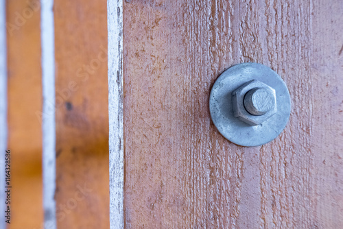 A metal screw with a nut screwed into a wooden board. photo