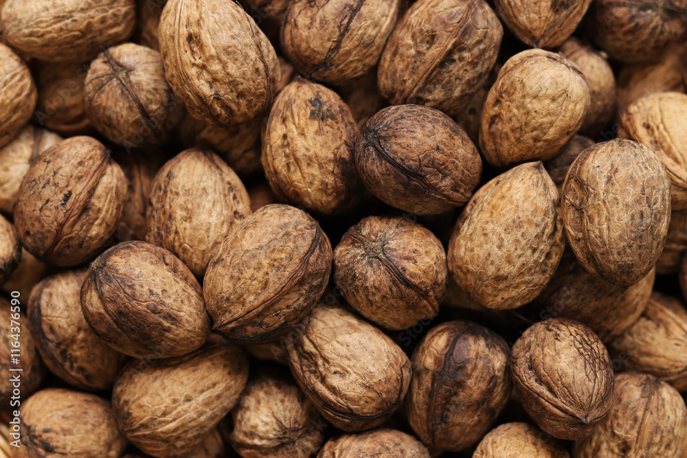 Heap of walnuts in shell, close-up, top view. Healthy eating. Harvest, agriculture. Walnuts, selective focus, background Heap of walnuts in shell, close-up, top view. Healthy eating. Harvest, agriculture. Walnuts, selective focus, background
