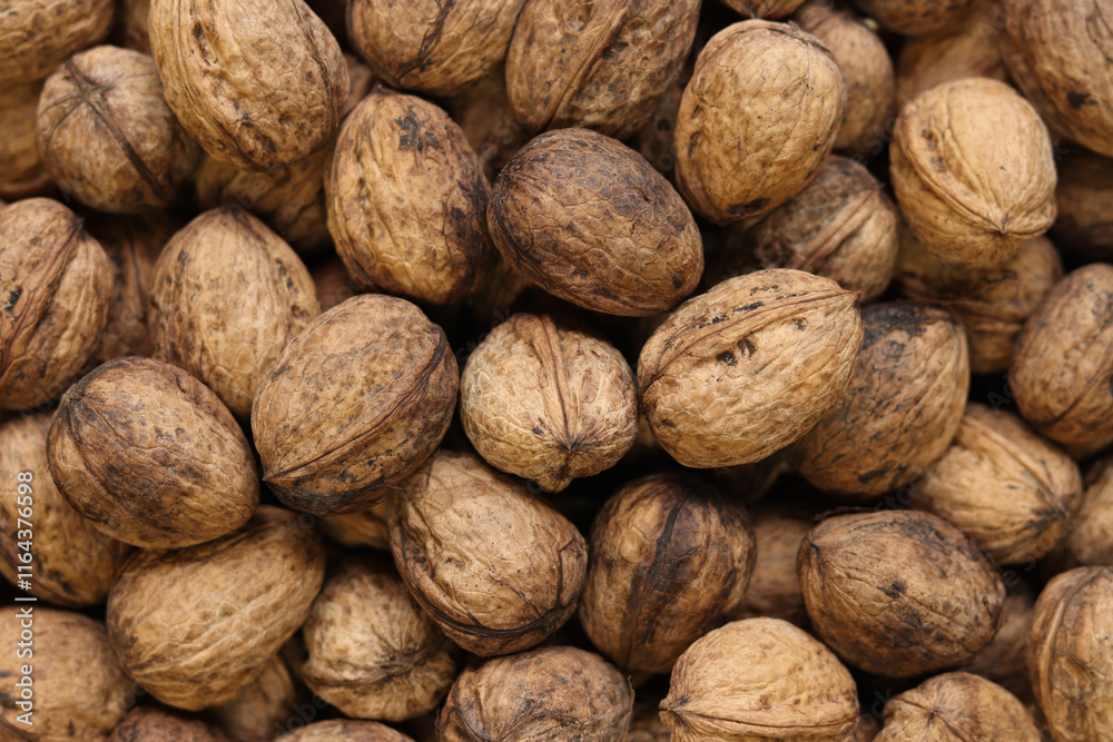 Heap of walnuts in shell, close-up, top view. Healthy eating. Harvest, agriculture. Walnuts, selective focus, background Heap of walnuts in shell, close-up, top view. Healthy eating. Harvest, agriculture. Walnuts, selective focus, background