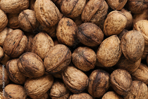 Heap of walnuts in shell, close-up, top view. Healthy eating. Harvest, agriculture. Walnuts, selective focus, background