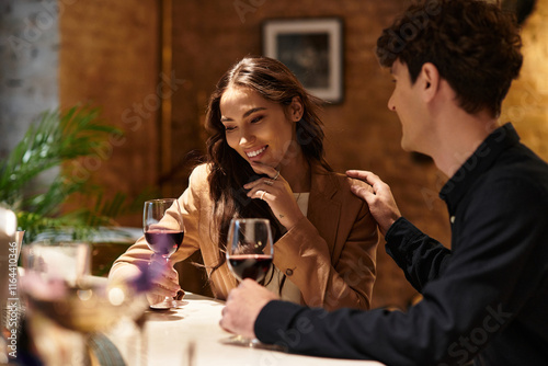 A couple shares intimate smiles and laughter while sipping wine in a charming restaurant.
