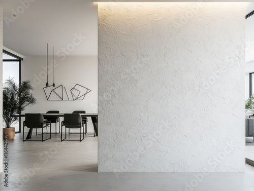 A white wall with a black chair in front of it. There is a plant in the corner