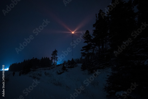 Obraz na płótnie Lighthouse Lit Up in Orange Color in the Forest at Night in Winter at Night in Anticosti Island, Quebec w salonie