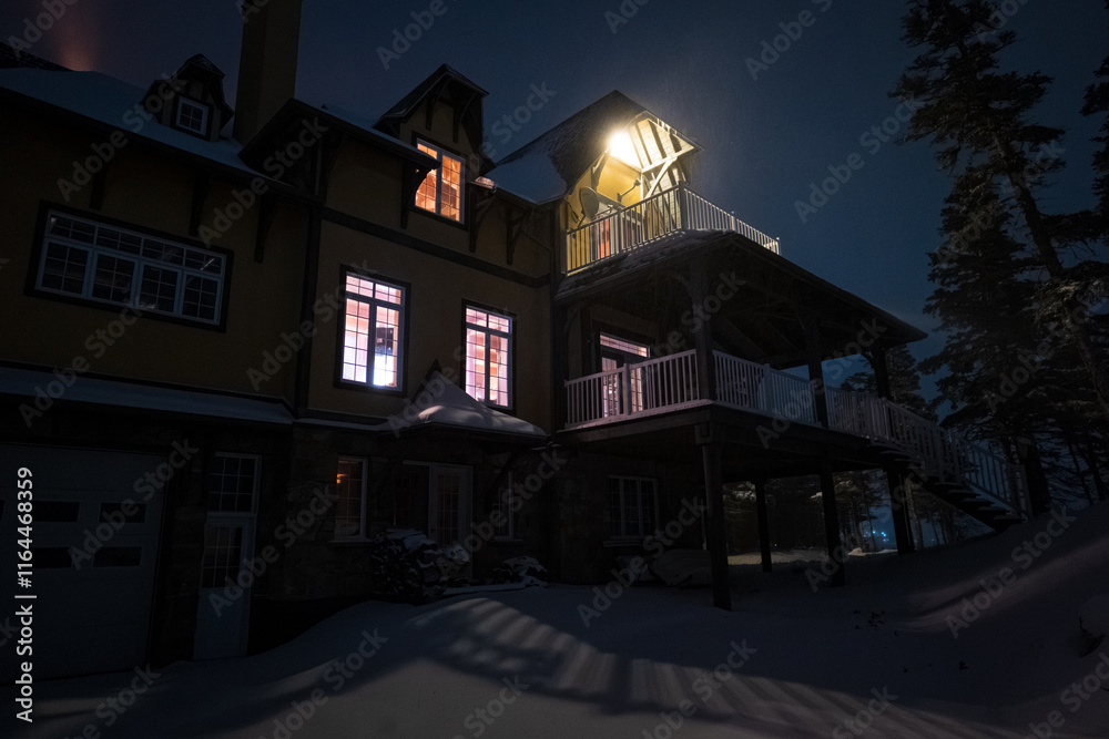 Mountain House Lit Up at Night in Winter Landscape in Anticosti Island, Quebec with Lighthouse Behind