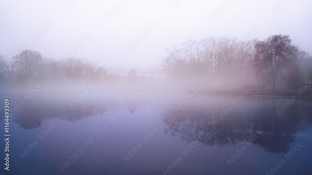 Fototapeta premium Foggy winter landscape with trees in the mist and snow-covered ice over the lake in New Haven, Connecticut, USA