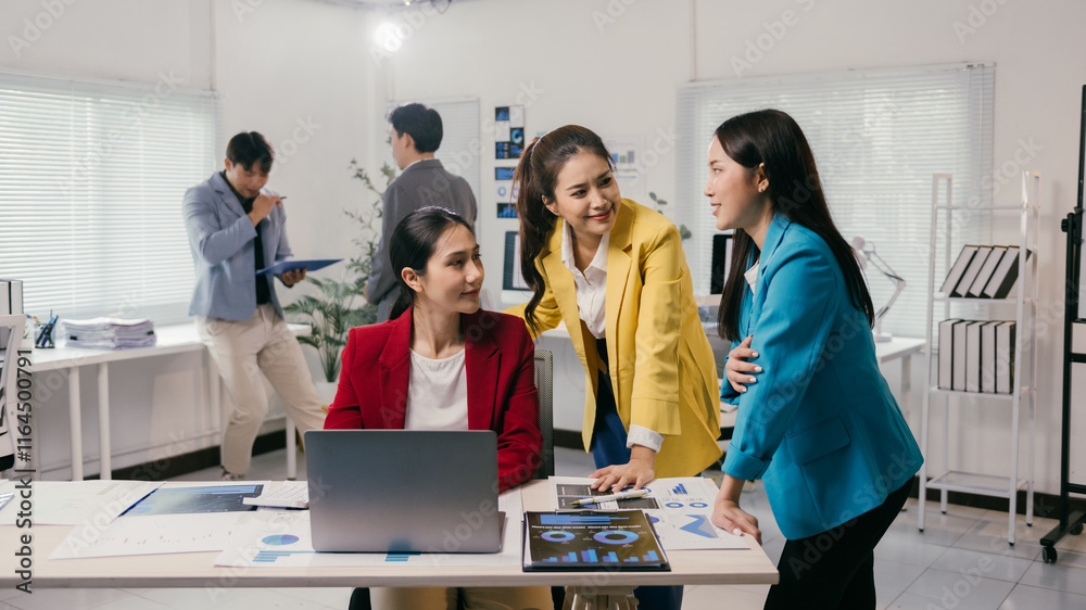 © Parichat - Three asian businesswomen are collaborating on a project. Using a laptop and analyzing charts in a modern office. Discussing strategies and sharing ideas while other colleagues work in the background © Parichat - Three asian businesswomen are collaborating on a project. Using a laptop and analyzing charts in a modern office. Discussing strategies and sharing ideas while other colleagues work in the background