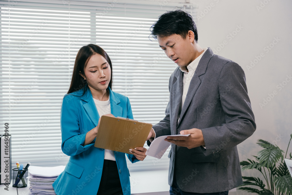 Two businesspeople are discussing documents in a modern office, demonstrating teamwork and collaboration as they review paperwork and engage in productive communication Two businesspeople are discussing documents in a modern office, demonstrating teamwork and collaboration as they review paperwork and engage in productive communication