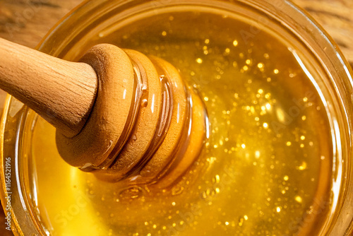 Close-up of a wooden spoon stirring honey in a small glass jar, with honey drips around the spoon, placed on a rustic wooden table. Soft lighting highlights the golden tones, ideal for food and wellne photo