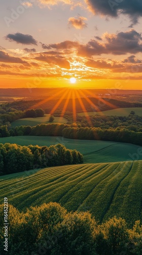 Breathtaking sunset over rolling hills and green fields in a serene countrysi...