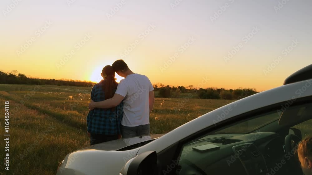 Married family couple in love hugging at sunset by car, romantically spending quiet time together, relaxing outside car. Husband and wife, spouses hugging, standing in field by car. Road trip, travel Married family couple in love hugging at sunset by car, romantically spending quiet time together, relaxing outside car. Husband and wife, spouses hugging, standing in field by car. Road trip, travel