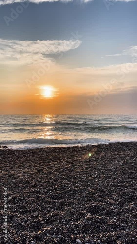 Sunset over the ocean viewed from a rcoky beach, capturing vibrant colors and wave reflections at golden hour