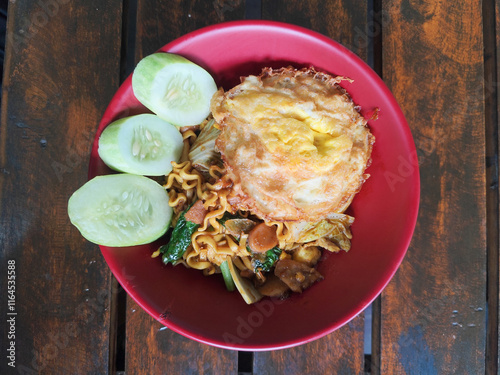 Mie Goreng Close Up, Fried Instant Noodles with Sunny Side Up Egg and Vegetables on Top. Popular Instant Noodles from Indonesia. photo