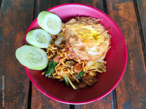 Mie Goreng Close Up, Fried Instant Noodles with Sunny Side Up Egg and Vegetables on Top. Popular Instant Noodles from Indonesia. photo