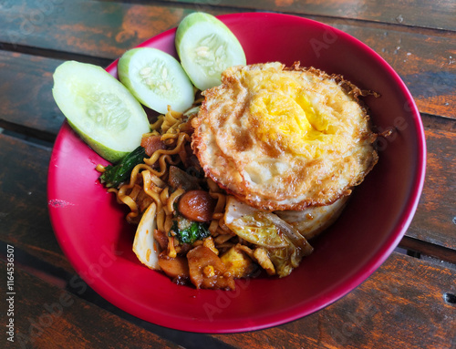 Mie Goreng Close Up, Fried Instant Noodles with Sunny Side Up Egg and Vegetables on Top. Popular Instant Noodles from Indonesia. photo