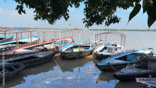 Boats anchored on the Ganges River on a sunny day in Assi ghat, Varanasi city, Uttar Pradesh, India photo