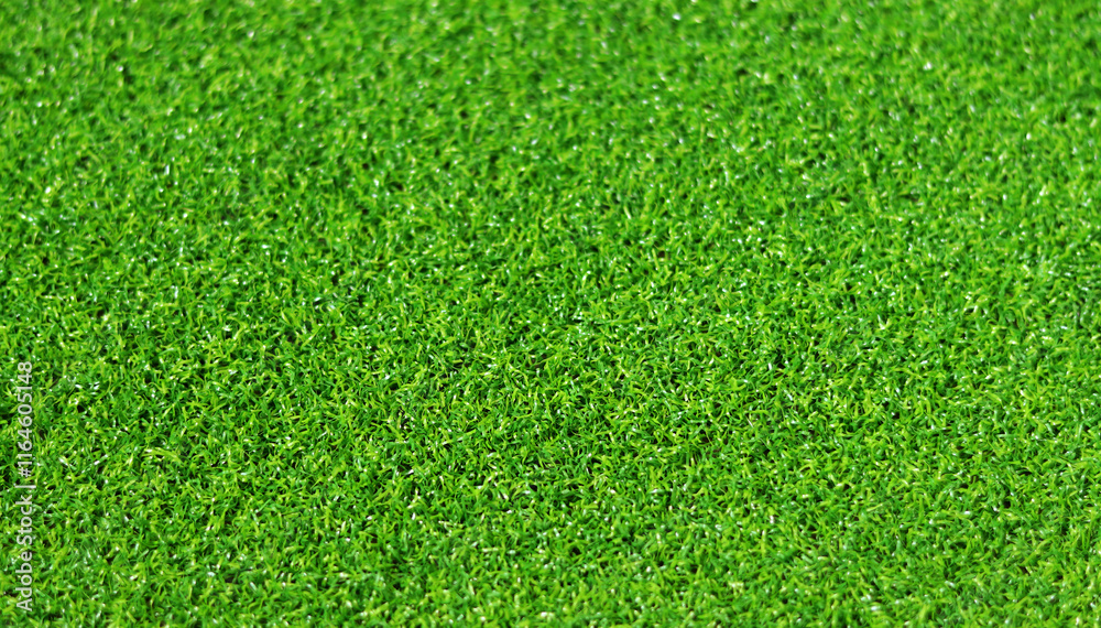 Fototapeta premium Artificial green grass mat, selective focus. Artificial turf, surface made of synthetic fibers. Green grass texture background. Short artificial grass golf surface