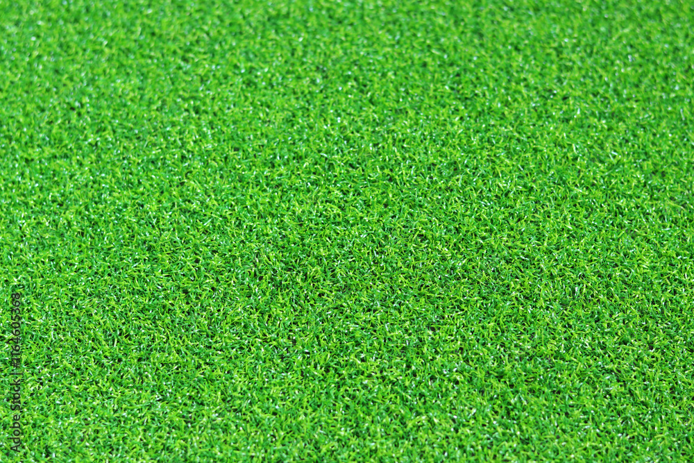 Fototapeta premium Artificial green grass mat, selective focus. Artificial turf, surface made of synthetic fibers. Green grass texture background. Short artificial grass golf surface
