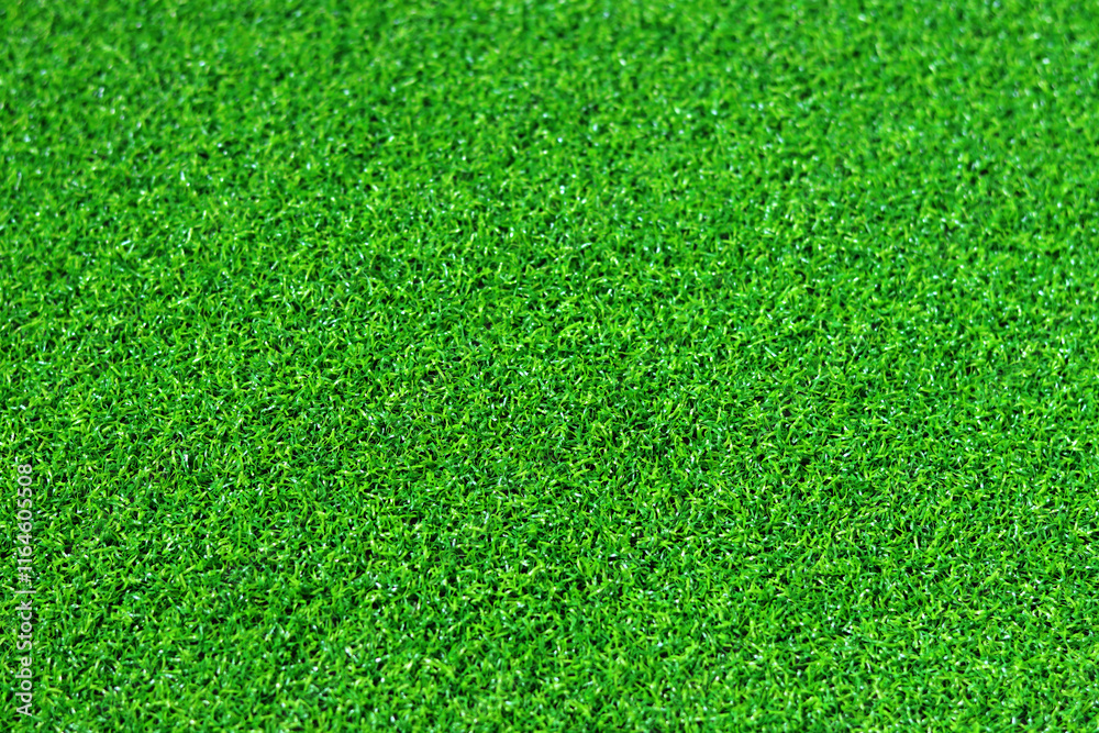 Fototapeta premium Artificial green grass mat, selective focus. Artificial turf, surface made of synthetic fibers. Green grass texture background. Short artificial grass golf surface