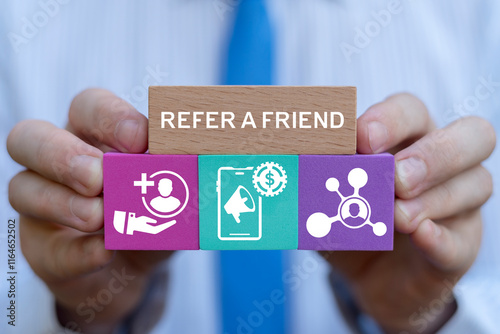 Obraz na płótnie Person holding colorful blocks with icons sees inscription: REFER A FRIEND. People making money from referral. Refer a friend or referral marketing business concept. Social media marketing for friends w salonie