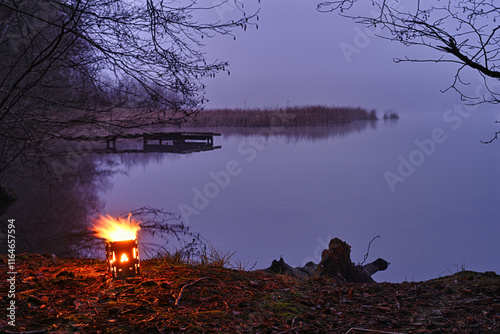 A bush box burns in the evening at the lake. photo