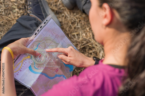 Woman using compass and map during orienteering race. Latin young venezuelan